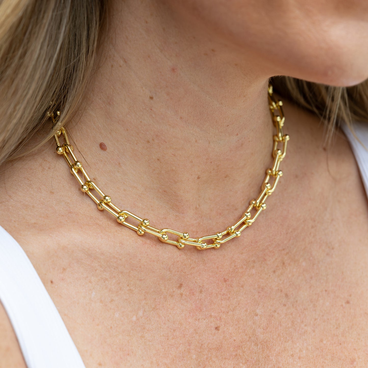 Gold horseshoe necklace on blonde woman's neck