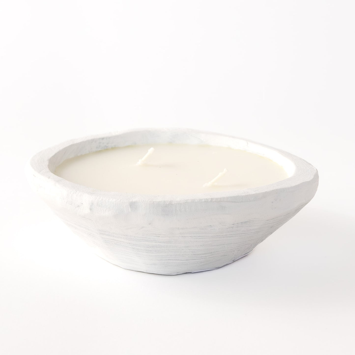 A small oval dough bowl candle with white wax, placed on a white surface.
