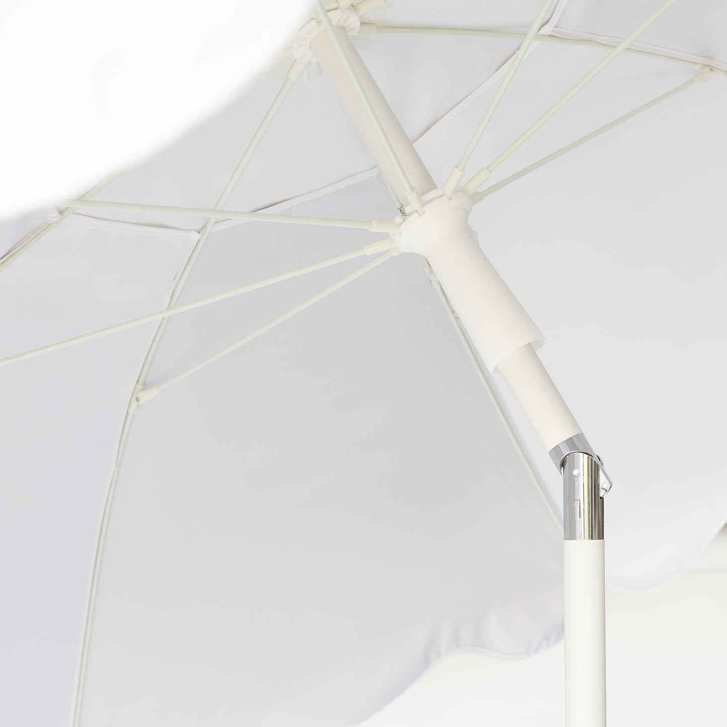 Close-up of a white and black beach umbrella with a metallic joint on a white background