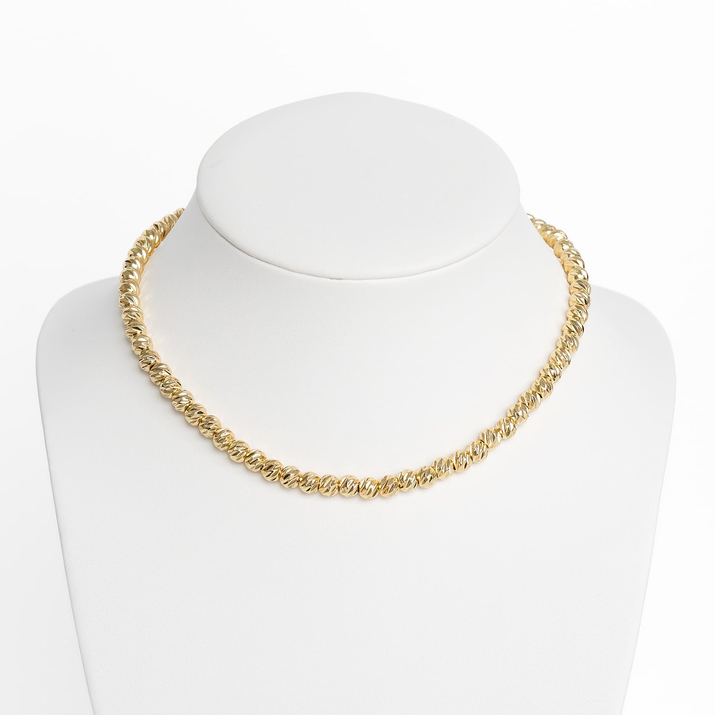 A gold-colored large beam necklace chain displayed on a white mannequin.