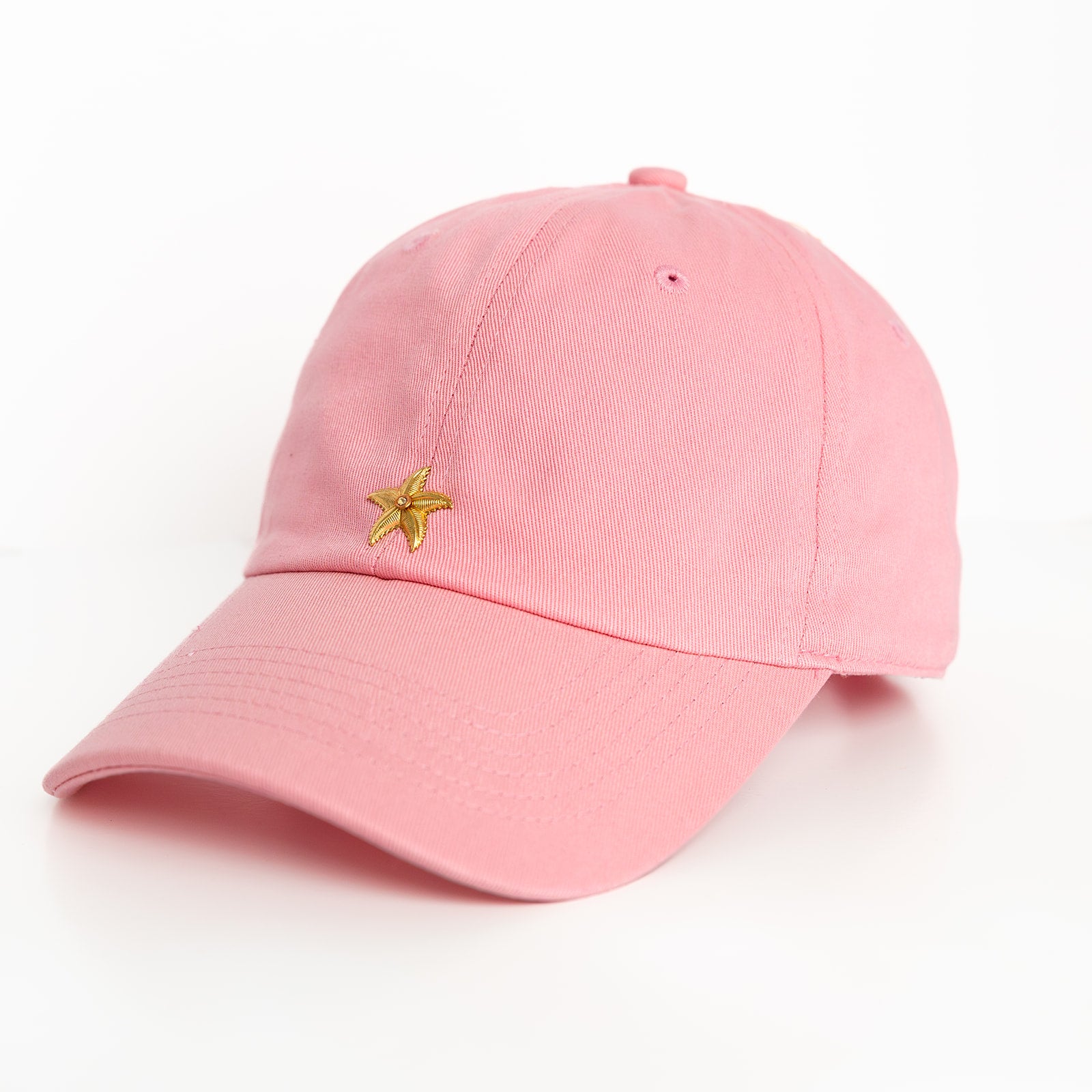 A pink baseball hat with a gold starfish emblem detail on the front.