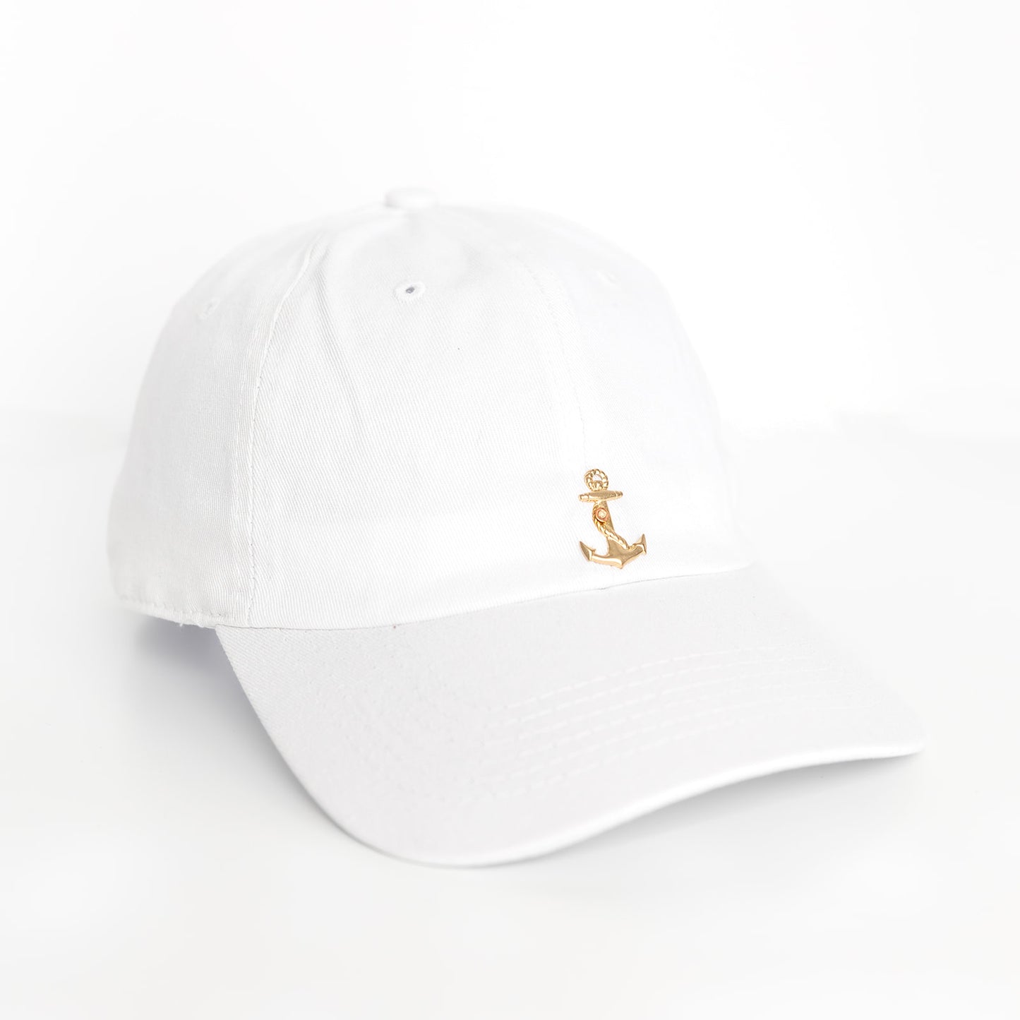 A white baseball cap with a gold anchor emblem on the front.