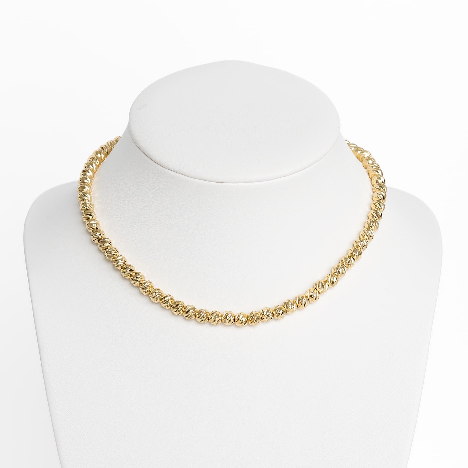 A gold-colored large beam necklace chain displayed on a white mannequin.